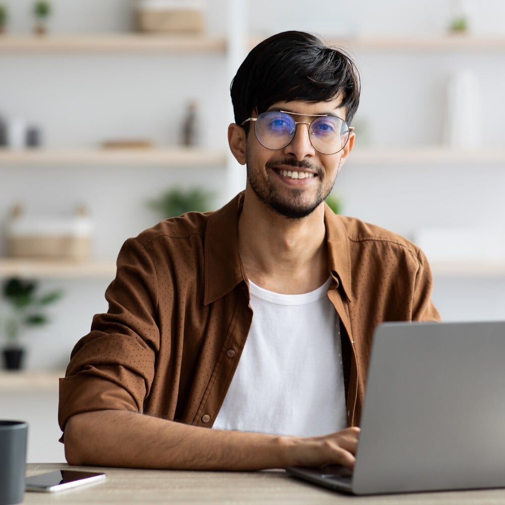 young indian man at computer smiling
